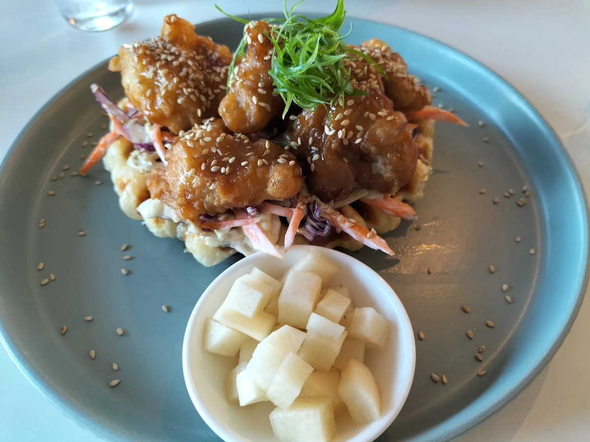 Crispy Fried Chicken Mixed in a Sweet and Spicy Sauce Atop Slaw and Buttery Croffle